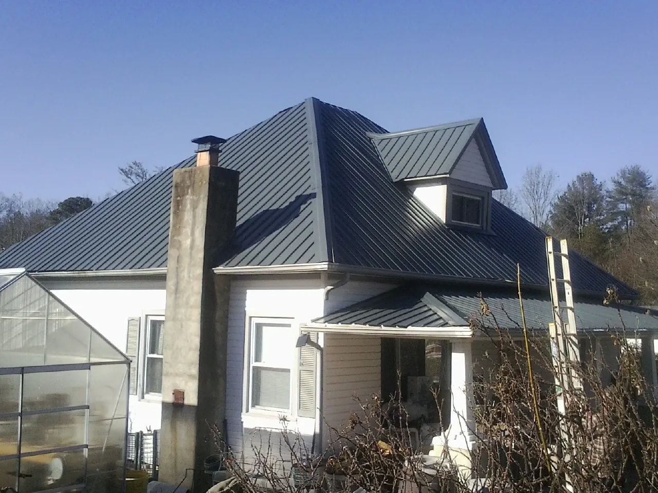 Dark blue standing seam metal roof on a white farmhouse with dormer — Slate & Tile Roof Repair by Roofing Brothers in Hales Corners