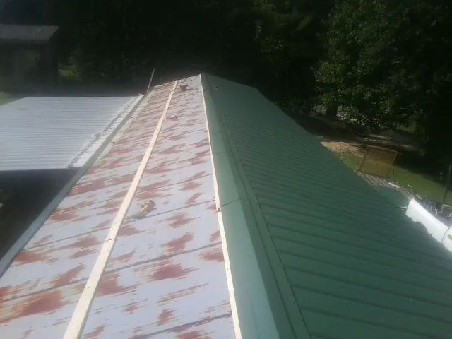 Old rusted panels beside newly installed green metal roofing — Wind Damage Roof Repair by Roofing Brothers in Hales Corners