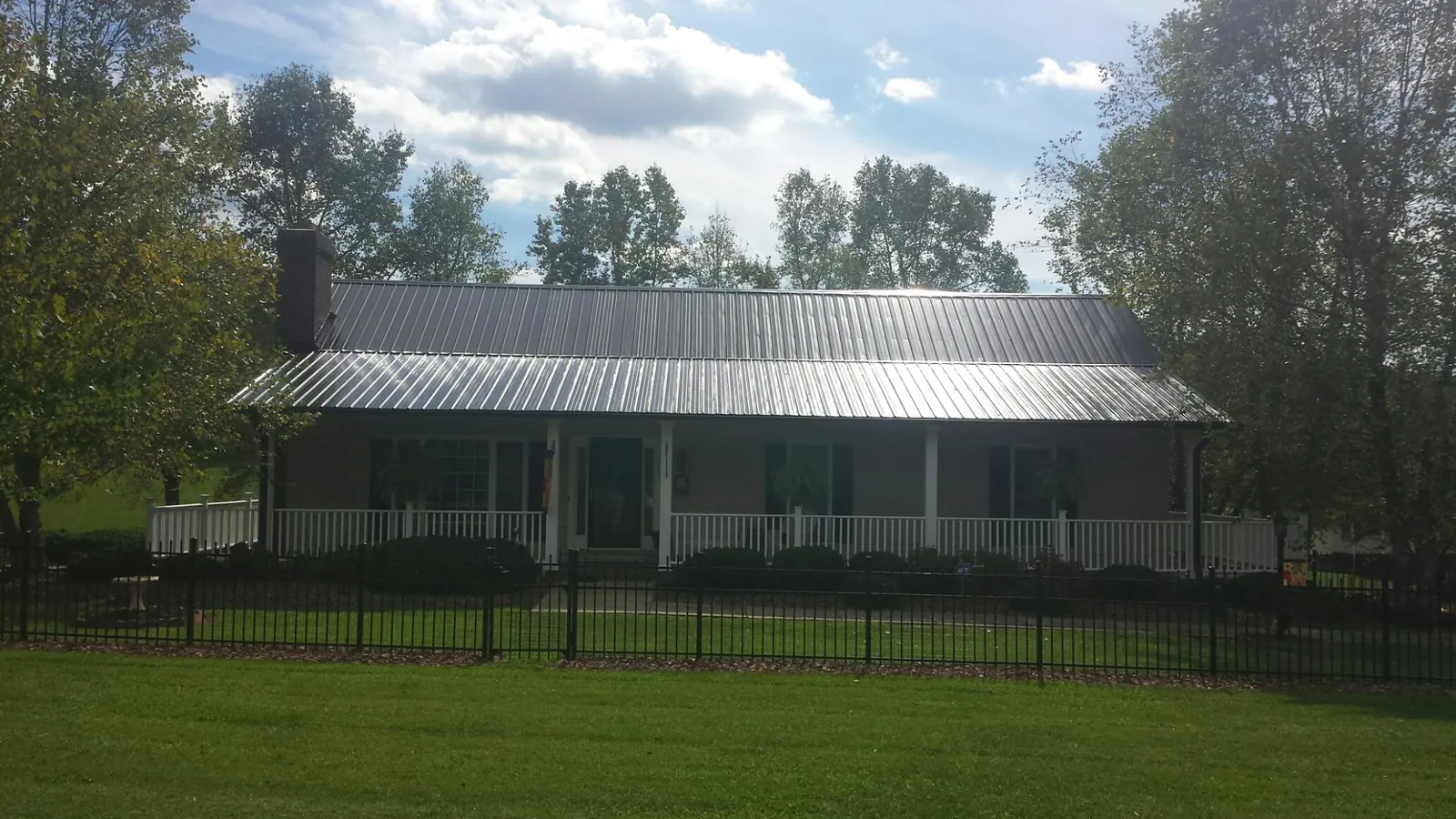 Gray metal roof on a brick ranch with a full width front porch — Gutter Guard Installation work by our crew in Hales Corners