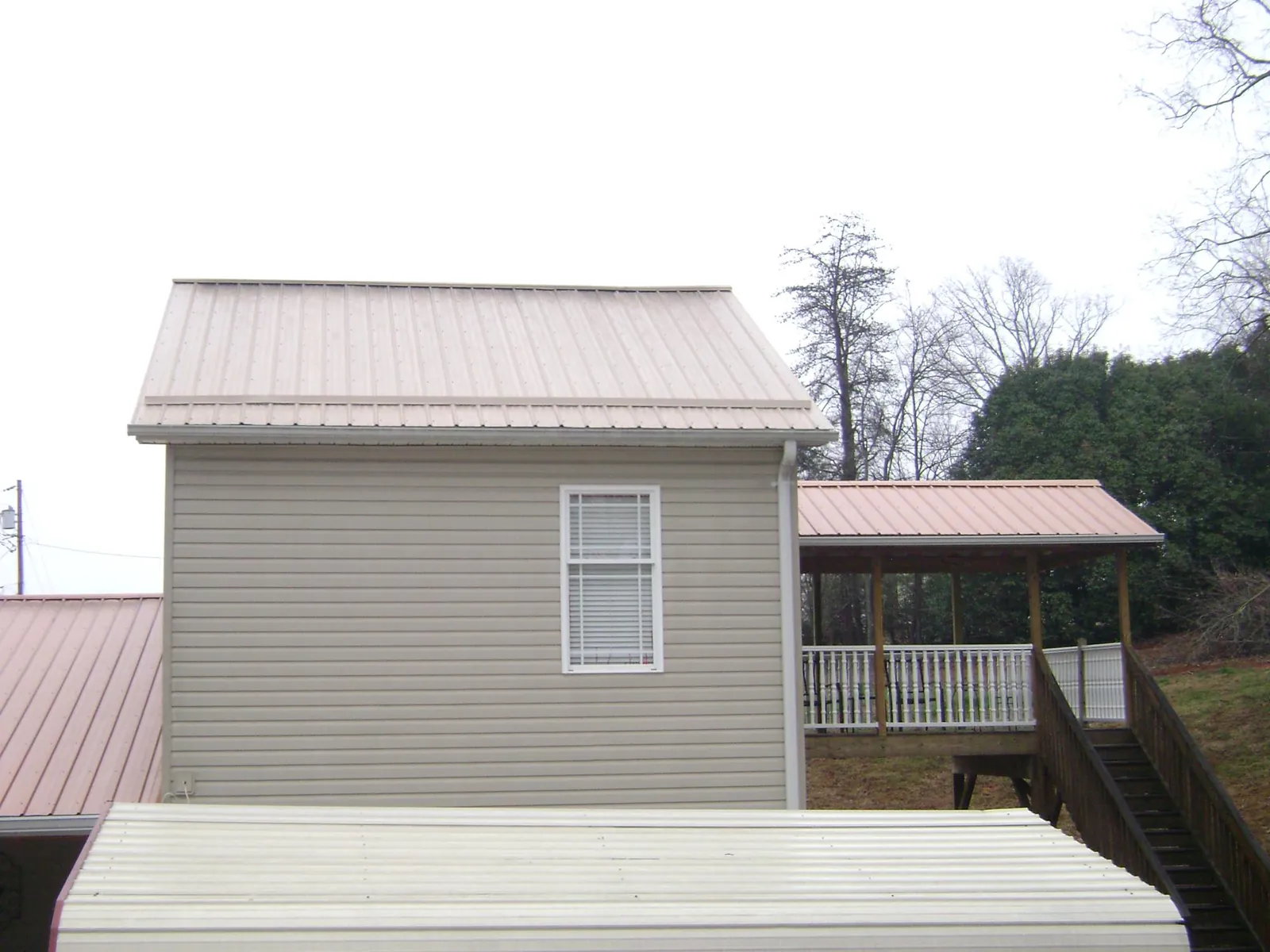 Tan metal roofs on a two story addition and attached porch, from a Roof Replacement job in Hales Corners